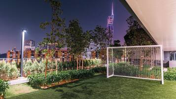 A well-maintained garden with a soccer goal, surrounded by neatly trimmed grass and various plants.
