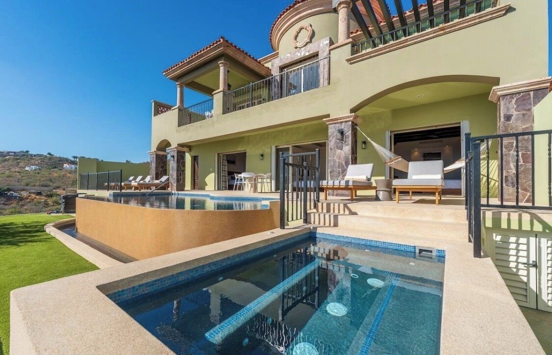 Ein zweistöckiges Haus mit Swimmingpool, Gartenmöbeln und Blick auf die Landschaft.