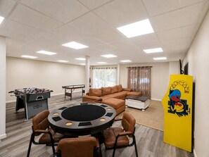 A room with a foosball table, pool table, brown leather sofa, and a yellow cabinet with a cartoon character. - Northwoods Lakefront Retreat! Swim, Fish, Relax (Rhinelander)