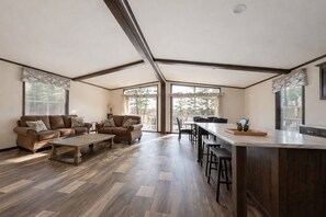 Ein geräumiges Wohnzimmer mit einer großen Couch, einem Couchtisch und einer Küchenzeile mit einer Bar und Hockern.