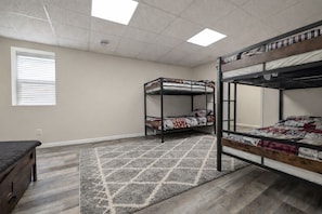A bedroom with two bunk beds, a small desk, and a window with blinds.