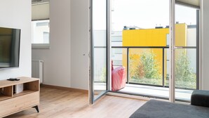 A modern room with a sliding glass door, a wooden floor, a flat-screen TV, and a sofa. - Modlińska Riverside Comfort Apartment (Warszawa)