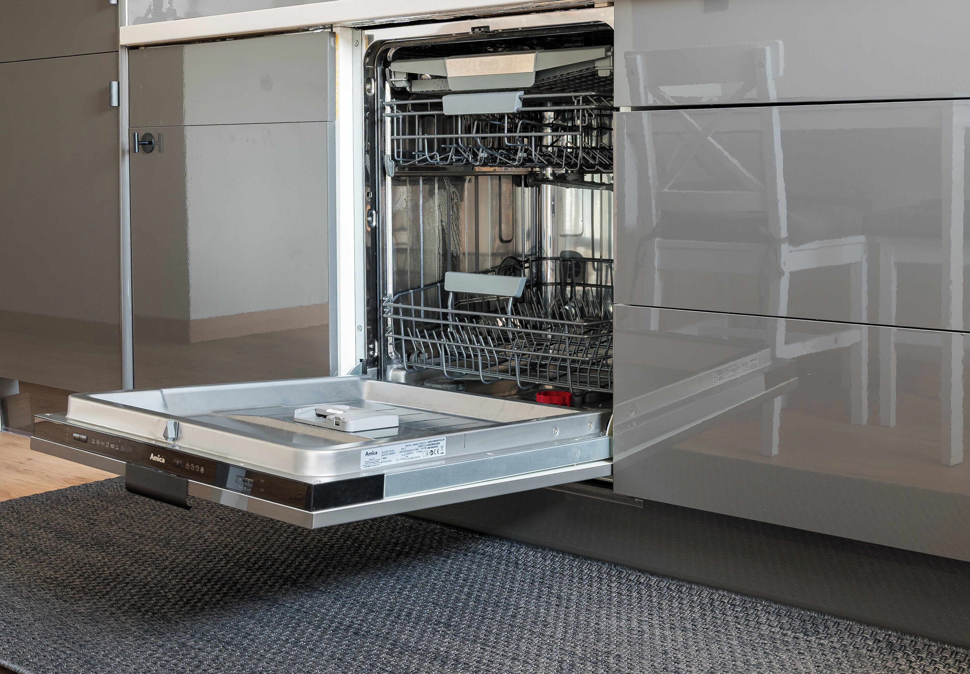 An open dishwasher with a control panel and a drying rack inside.