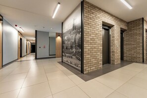 Un couloir moderne avec un sol carrelé, une grande photo en noir et blanc accrochée au mur et un mur d’accent en briques.