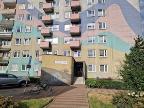 A multi-story building with balconies, a bicycle, and a sign indicating a parking area.