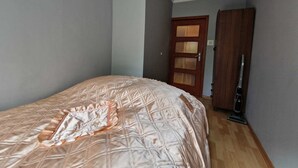 Une chambre à coucher avec un lit, une porte en bois et un aspirateur.