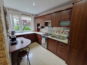 A kitchen with a gas stove, sink, and wooden cabinets.