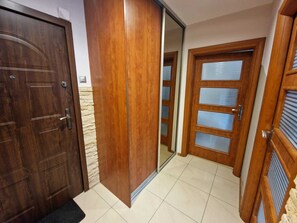A hallway with wooden doors, one of which is open revealing a mirrored closet.
