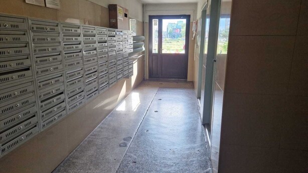 Un couloir avec des étagères métalliques sur le côté gauche et une porte au fond.