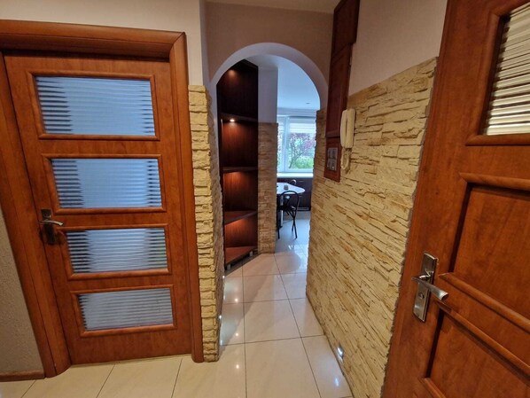 A hallway with wooden doors, stone walls, and a tiled floor.