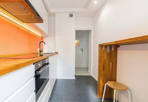Eine Küche mit einer Holzausziehtafel, einem Backofen und einem Hocker.