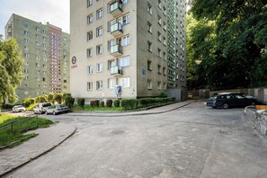 A multi-story residential building with balconies, a paved driveway, and parked cars. - Spadzista Comfort Apartment (Gdańsk)