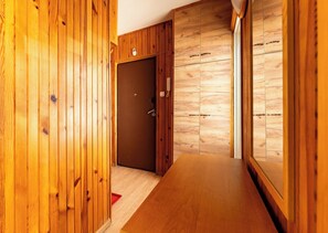 A wooden interior hallway with a door, a small table, and a wall with a patterned design. - Spadzista Comfort Apartment (Gdańsk)