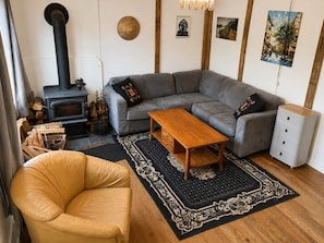 Una sala de estar acogedora con un sofá, una mesa de centro de madera, un sillón de cuero, una chimenea y una alfombra.