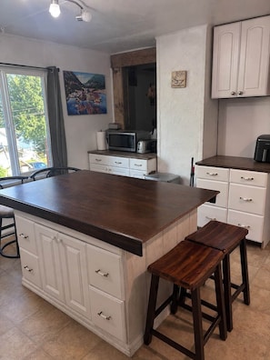 Una cocina con una isla grande, armarios blancos y vistas al exterior.