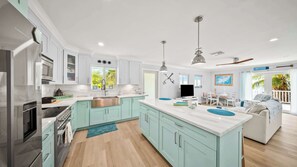 A modern kitchen with white cabinets, a central island, and a dining area with a view. - Oceanfront Beach House 3BR|3BA Newly renovated (Marathon)
