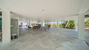 A covered outdoor area with a concrete floor, a wooden bench, and a table. - Oceanfront Beach House 3BR|3BA Newly renovated (Marathon)