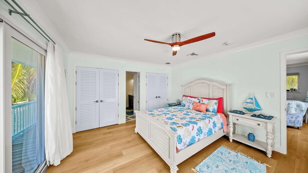 A bedroom with a bed, a nightstand, a ceiling fan, and a view of the outside. - Oceanfront Beach House 3BR|3BA Newly renovated (Marathon)