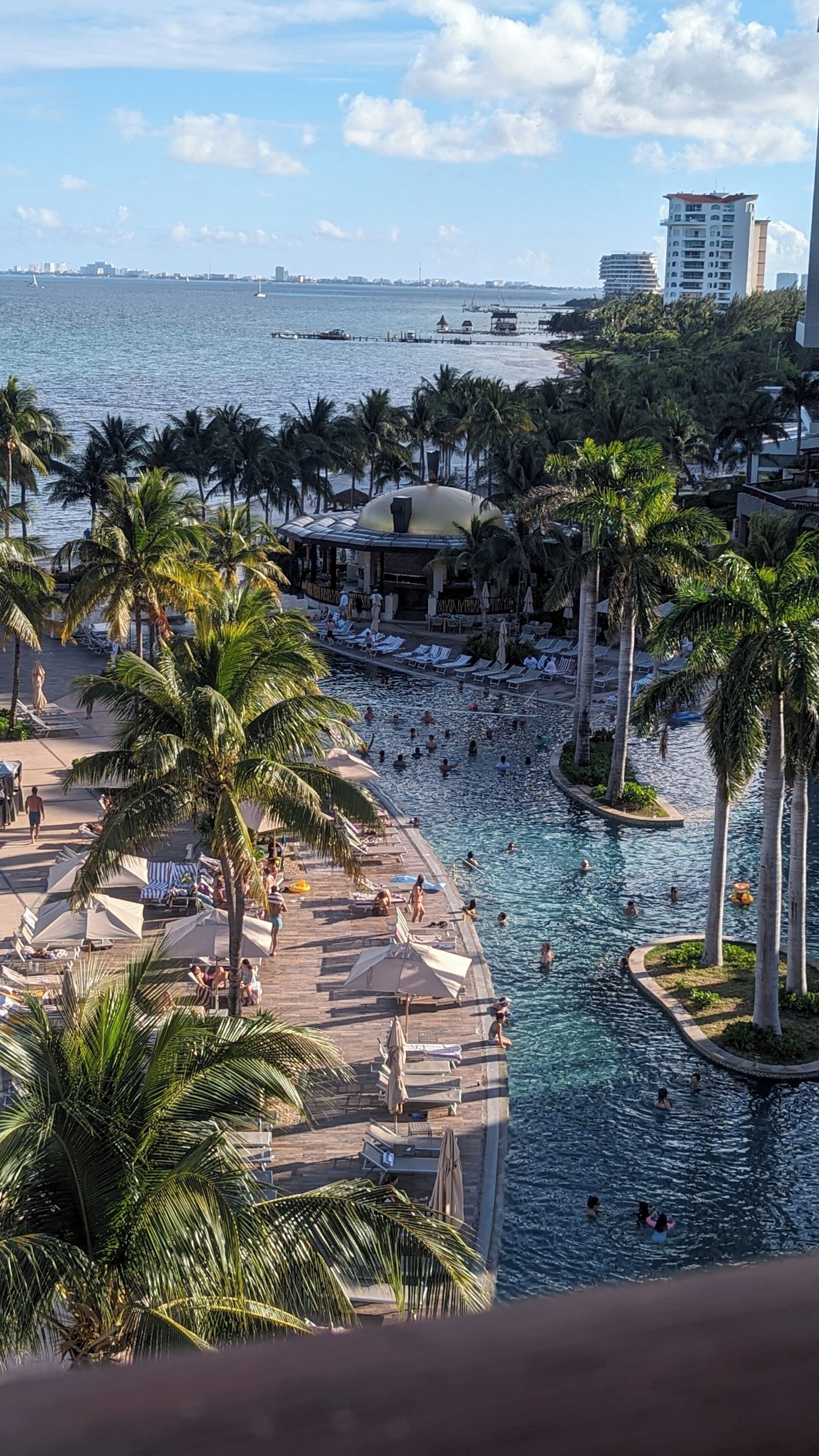 A resort with a swimming pool, palm trees, and a view of the ocean.