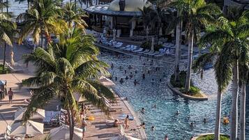 A resort with a swimming pool, palm trees, and a view of the ocean.
