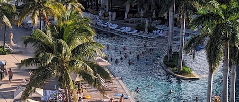 A resort with a swimming pool, palm trees, and a view of the ocean.