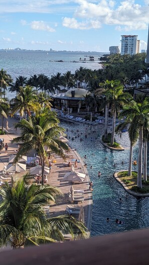 A resort with a swimming pool, palm trees, and a view of the ocean.