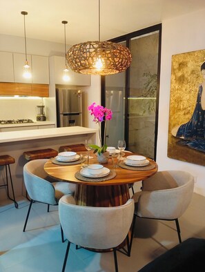 A modern dining area with a round wooden table, six chairs, and a central vase with flowers.