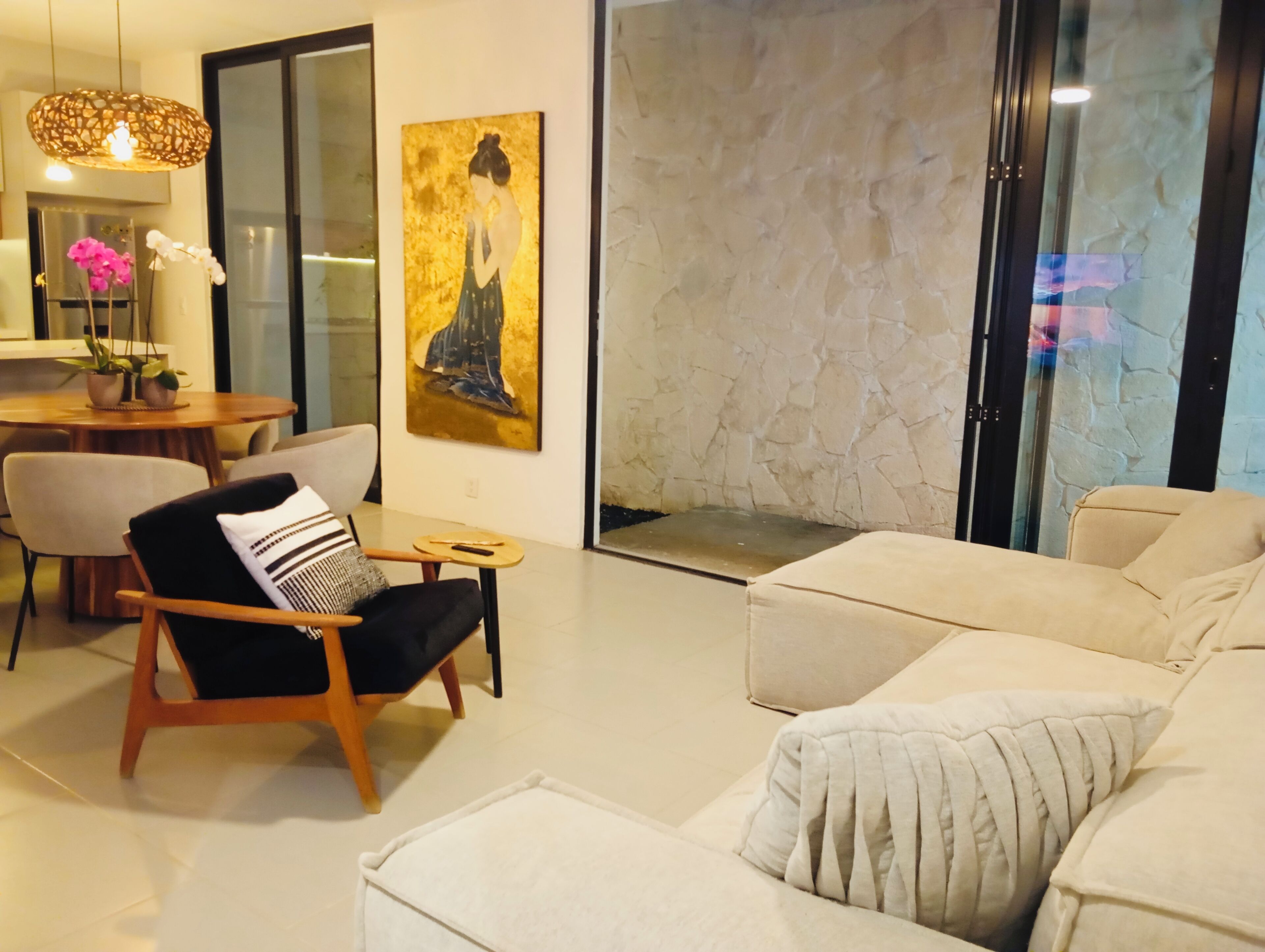 A modern living room with a sofa, armchair, and a painting on the wall.