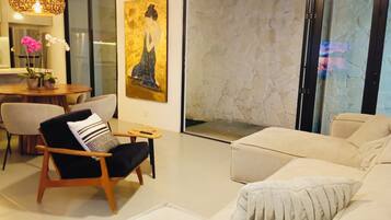 A modern living room with a sofa, armchair, and a painting on the wall.
