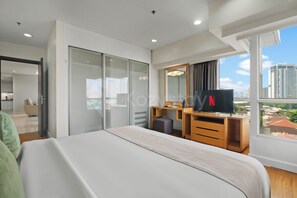 Ein modernes Hotelzimmer mit Bett, Schreibtisch, Spiegel und Fernseher.