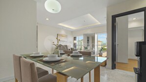 A modern dining area with a glass table, chairs, and a view of the cityscape through large windows. - Solea by Kozystay - Senayan (South Jakarta)