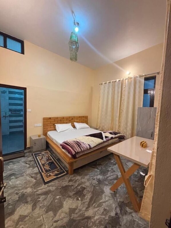 A bedroom with a bed, bedside table, and a hanging light fixture.