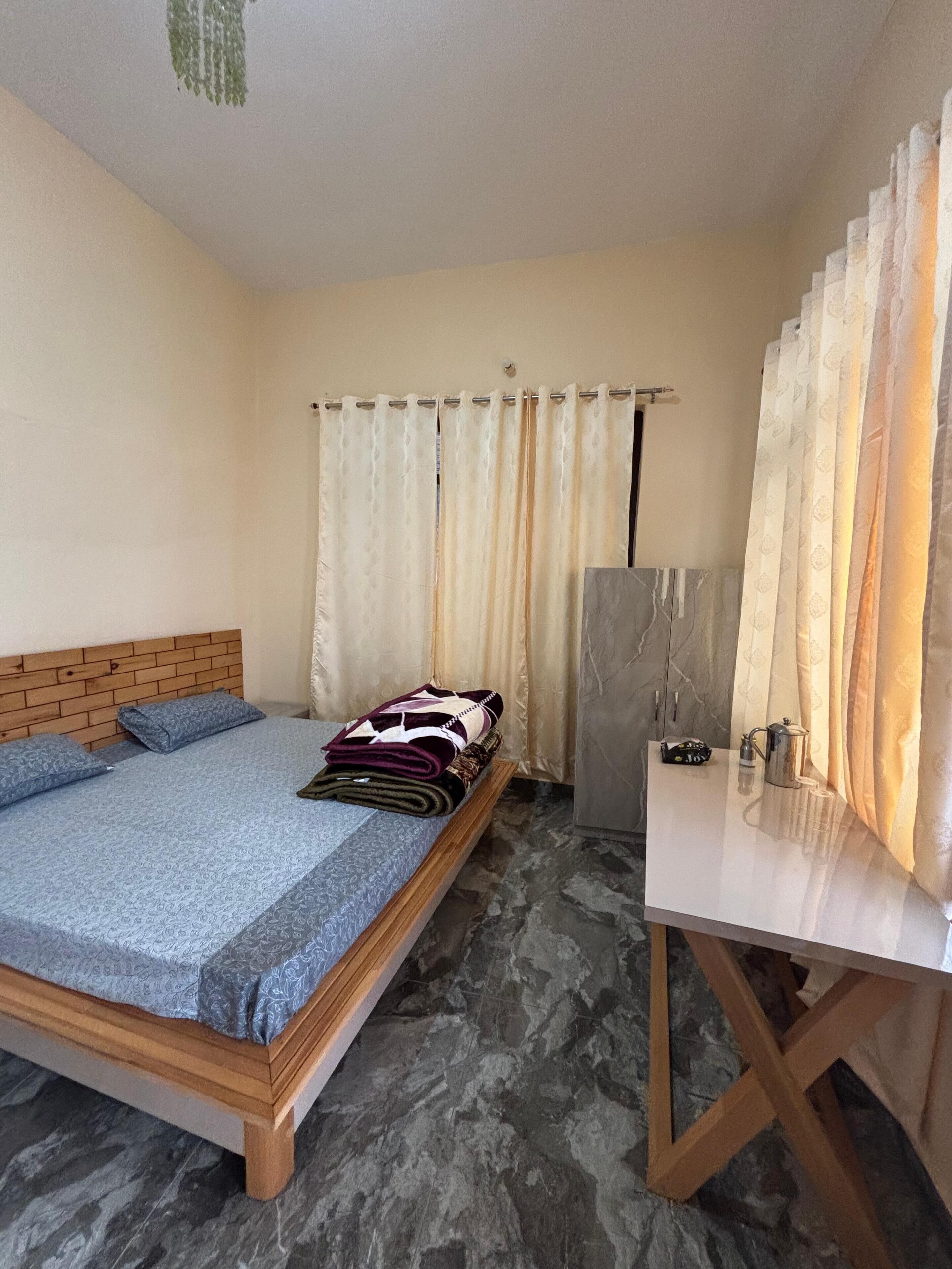 Un dormitorio con una cama, una mesita de noche con un hervidor y cortinas.