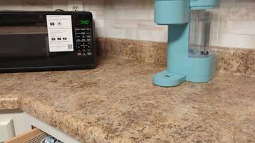 A kitchen with a microwave, a coffee machine, and a drawer with yogurt containers.