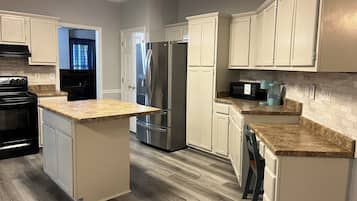 A modern kitchen with a central island, stainless steel appliances, and light-colored cabinetry.