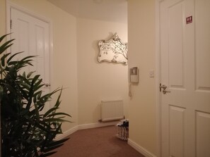 A hallway with white doors, a radiator, a telephone, and a decorative wall piece. - Relaxing exscape M4 Bridgend, Pothcawl 10 min to the seafront (North Cornelly)