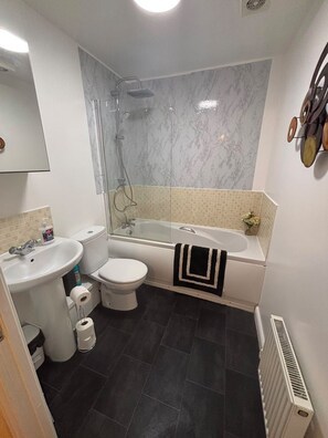 Un baño con ducha, inodoro, lavamanos y bañera.