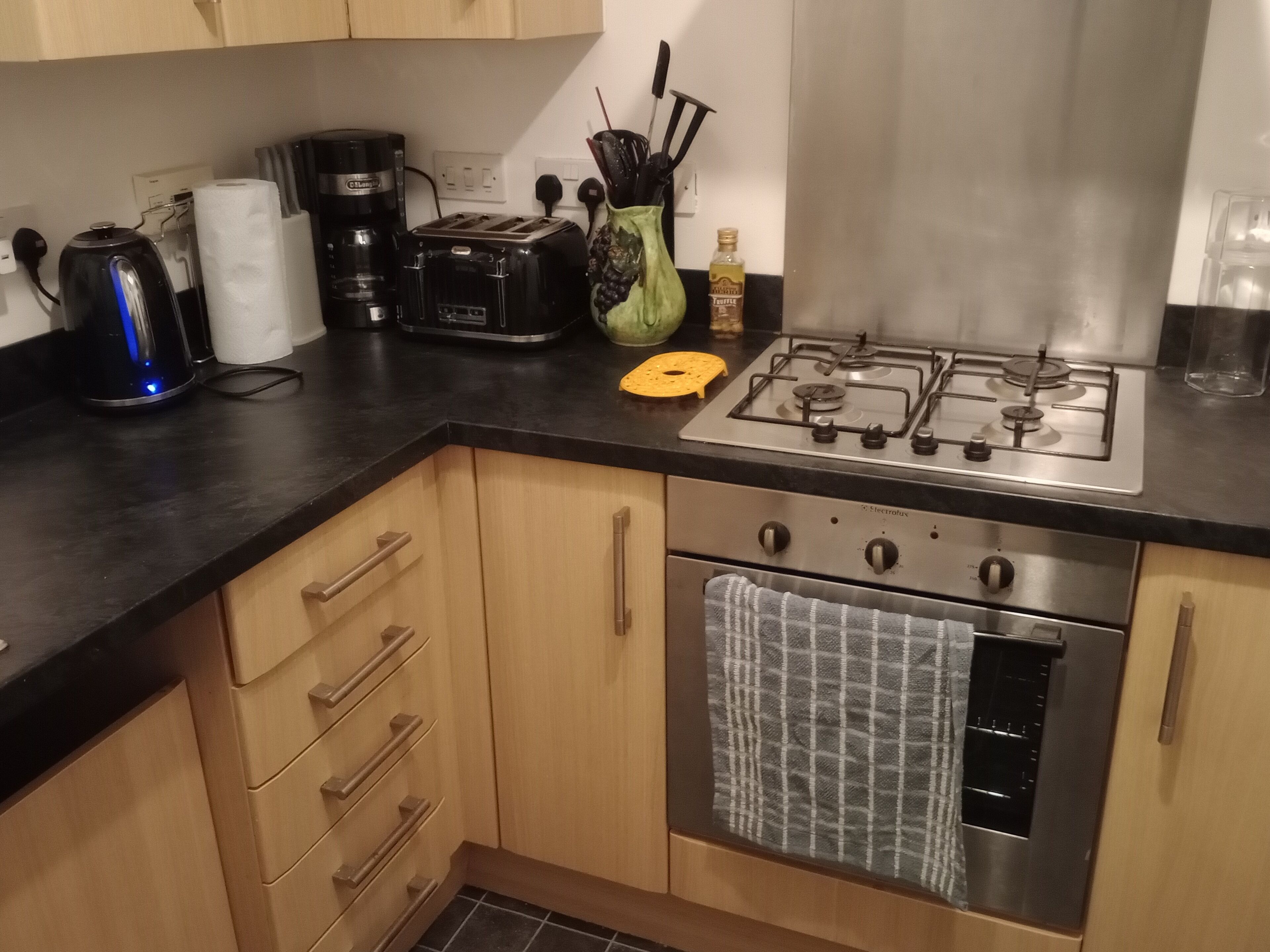 Una cocina equipada con estufa a gas, horno, tostadora, hervidor y diversos utensilios de cocina.