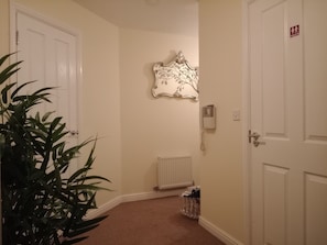 A hallway with white doors, a radiator, a telephone, and a decorative wall piece. - Prescott Seaside M4 Porthcawl beach (North Cornelly)