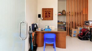 Una habitación con escritorio, una silla azul, un separador de madera y un aire acondicionado instalado en la pared.