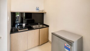 Una cocina compacta con refrigerador, pileta y microondas.