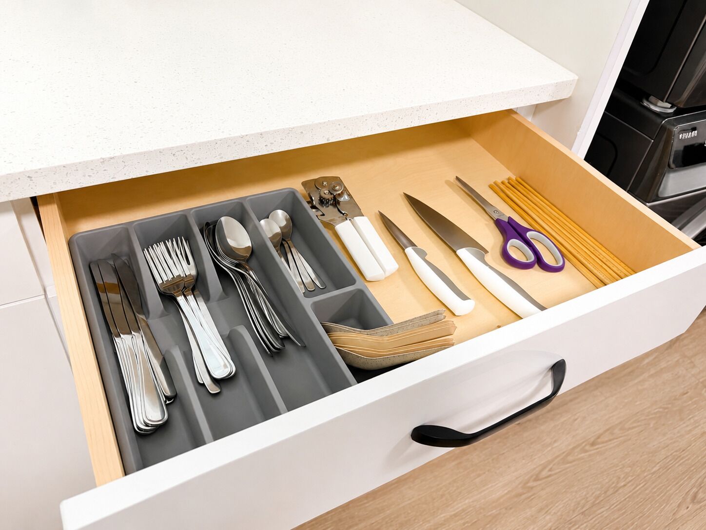 A drawer with utensils, including forks, spoons, and knives, neatly organized.