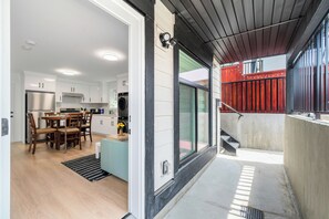 Una cocina moderna con armarios blancos, un refrigerador de acero inoxidable y un comedor con sillas y una mesa de madera.