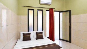 Une chambre d’hôtel avec un lit, une fenêtre avec des rideaux et un appareil de climatisation.