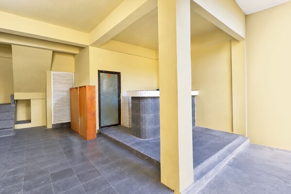 A corridor with a tiled floor, a wooden door, and a glass door with a frosted pattern.
