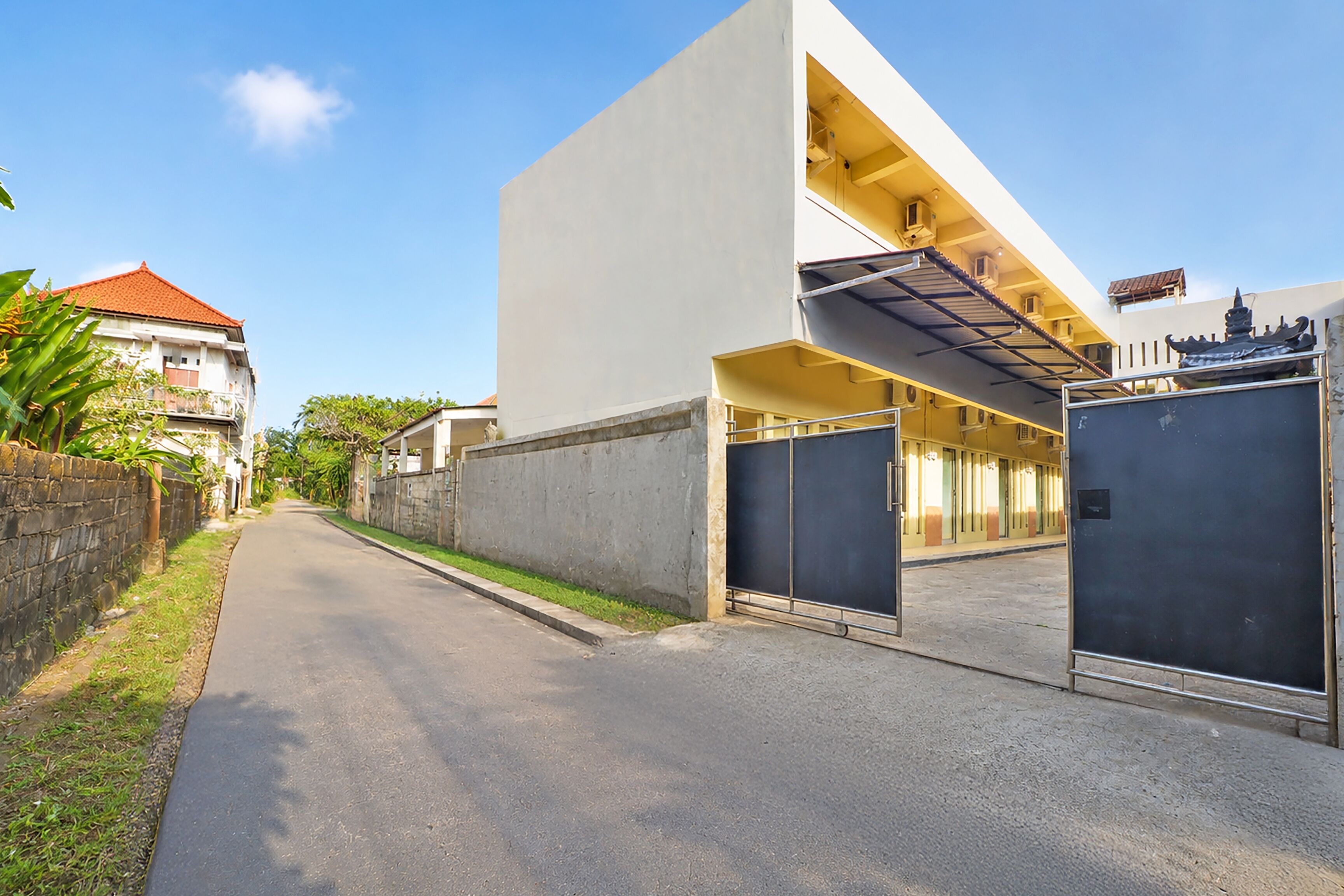 A modern building with a flat roof, a gated entrance, and a clear sky.