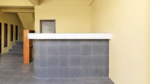Un comptoir d’accueil avec un revêtement de carrelage gris, un escalier en bois sur la gauche et une porte sur laquelle figure le chiffre « 0 ».