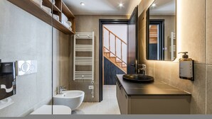 Un baño moderno con un bidé, un lavamanos, un espejo y un perchero para toallas.