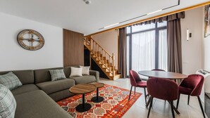 Una sala moderna con sofá, mesa de centro, alfombra y comedor con sillas y mesa.