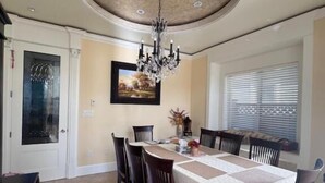 A dining room with a round ceiling, chandelier, and a table set for six.